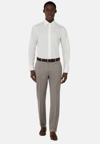 Camicia bianca a maniche lunghe con colletto a punta, abbinata a pantaloni a righe grigio chiaro e una cintura in pelle marrone scuro. Le scarpe marroni completano l'outfit.