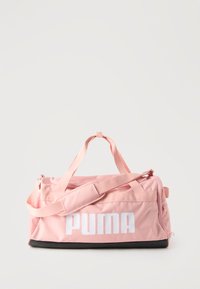 Ροζ αθλητική τσάντα PUMA με λευκό λογότυπο, επάνω λαβές, ιμάντα ώμου, πλαϊνή τσέπη με φερμουάρ και μαύρη βάση σε απλό φόντο.