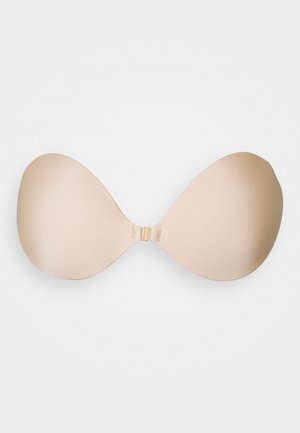 Soutien-gorge adhésif nude avec des coques lisses et sans couture, et un fermoir central. Le matériau a une finition mate douce et une forme ergonomique pour plus de confort.
