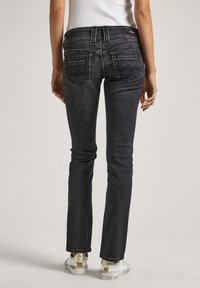 Czarne dżinsy o dopasowanym kroju, z średnim stanem, klasycznym pięciopocketowym stylem oraz subtelnym przeszyciem na tylnych kieszeniach.
