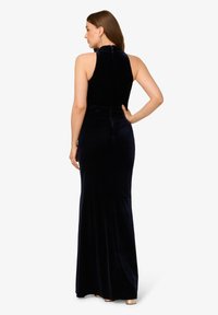 Sukienka wieczorowa z aksamitnego materiału w głębokim granacie, z dopasowanym górnym partem, bez rękawów oraz zwiewnym dołem. Posiada wysoki dekolt oraz zamek błyskawiczny z tyłu.
