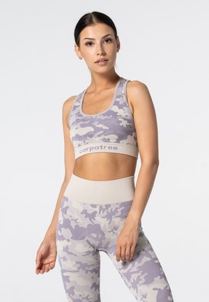 Sportowy zestaw stanik i legginsy w kolorze lawendy z kamuflażowym wzorem i szerokim beżowym pasem. Wykonany z elastycznego materiału, z dekoltem w serek.