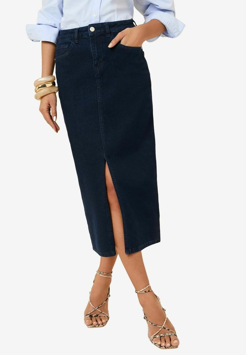 Donkere denim midi-rok met een voorknit, met een gladde textuur, knoopsluiting en riemlussen. Draagt met sandalen met bandjes en houten armbanden.