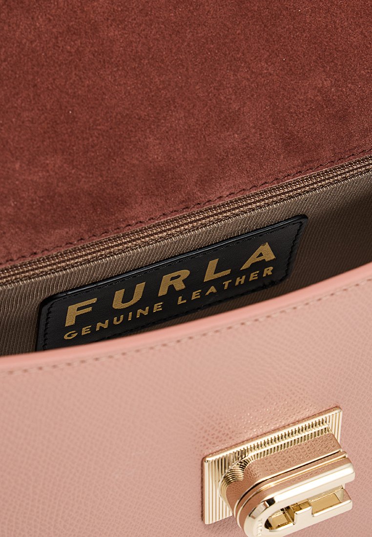 Innenansicht eines rosa Lederhandbags mit einem braunen Wildlederfutter. Enthält einen Verschluss in Goldoptik und ein schwarzes Etikett mit den Aufschriften "FURLA" und "ECHTES LEDER".
