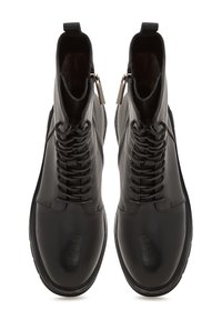 Botines de cuero negro con un acabado suave, que cuentan con un cierre de cordones en la parte frontal, cremallera lateral y suela antideslizante. Forro suave visible en la apertura.