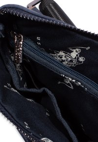 Interno in tela navale di una borsa con chiusura a zip, caratterizzato da una finitura testurizzata e da un motivo leggero che ripete figure sportive.