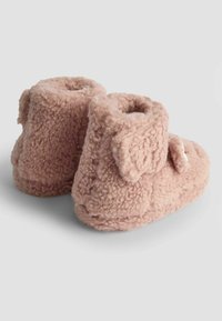 Mjuka rosa stövlar gjorda av texturerat fluffigt tyg med rundade toppar, prydda med små dekorativa öron och en sidoknapp.