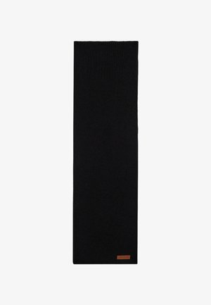 Abrigo largo de lana gris con solapas con muesca, bufanda negra de canalé, camiseta negra y jeans azul claro. El conjunto se completa con mocasines negros.