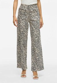 Löysät housut, joissa on vaaleanbeige ja harmaa zebra-kuvio, valmistettu pehmeästä kankaasta, korkea vyötärö ja sivutaskut.