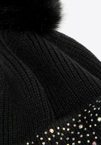 Cappellino nero lavorato a maglia con una texture a costine, caratterizzato da un pon pon soffice sulla cima e una fascia decorata con strass colorati.