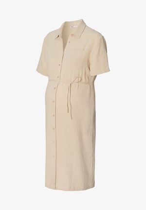 Jasno beżowa sukienka ciążowa z teksturowanej tkaniny, z krótkimi rękawami, zapinana na guziki z przodu oraz z paskiem do samodzielnego zawiązania w talii.