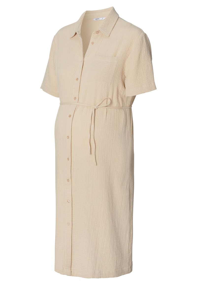 Jasno beżowa sukienka ciążowa z teksturowanej tkaniny, z krótkimi rękawami, zapinana na guziki z przodu oraz z paskiem do samodzielnego zawiązania w talii.