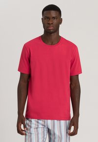 Maglietta a maniche corte in cotone di un brillante colore rosa, con scollatura rotonda e vestibilità morbida. Abbinata a pantaloni da pigiama a righe.