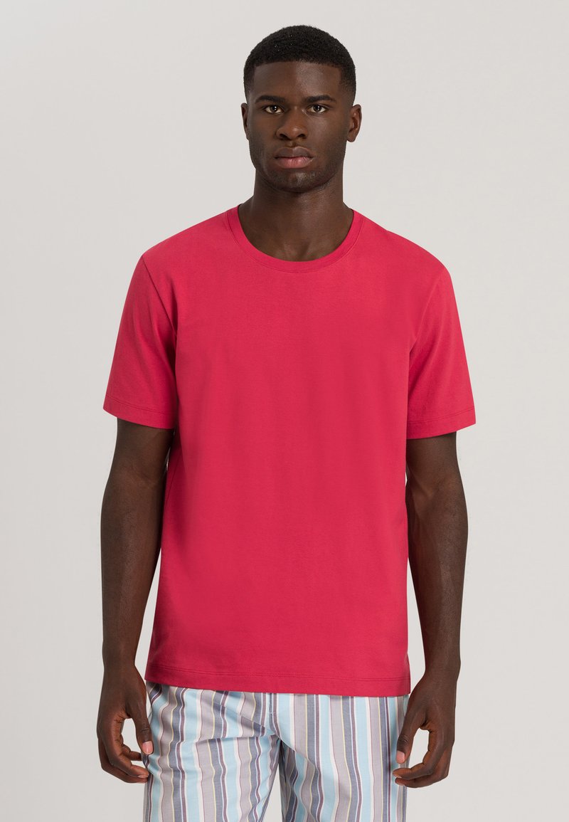 Maglietta a maniche corte in cotone di un brillante colore rosa, con scollatura rotonda e vestibilità morbida. Abbinata a pantaloni da pigiama a righe.