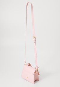 Small pink leather crossbody bag with a structured shape, gold hardware, and adjustable strap, featuring a folded flap design.