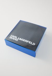 Čierny rebrovaný pletený sveter poskladaný v modrej krabici s priesvitným vekom, označený bielym textom "Karl Lagerfeld Jeans".