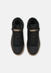 Svarta Puma-sneakers med gummisulor, snörning framtill och kardborreband märkta med Puma-logotyp, med en mjuk inre foder.