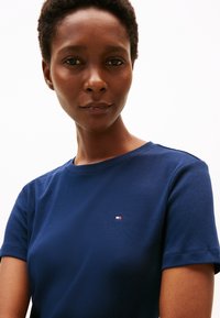 Navy blue cotton T-shirt featuring a crew neck, short sleeves, and a small logo with red, white, and blue accents on the chest.