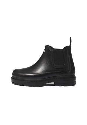Bottine noire en cuir avec semelle épaisse, panneau latéral élastique, languette à l’arrière et étiquette blanche partielle avec texte sur la partie supérieure avant.