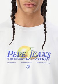 Hvit bomull T-skjorte med en fargerik sitron grafikk og fet tekst "PEPE JEANS LONDON." Rund hals og korte ermer med en avslappet passform.