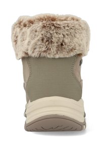 Botín de mujer con parte superior de textil beige, cuello de piel sintética y suela de goma. Presenta una forma redondeada y una apertura acolchada para mayor comodidad.