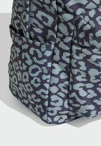 Bolso azul marino con estampado de leopardo en azul claro, fabricado con tela texturizada. Cuenta con bolsillos exteriores y un diseño estructurado y cuadrado.