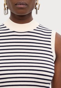 Striped sleeveless top featuring a cream base with navy horizontal stripes, rounded neckline, and ribbed texture.