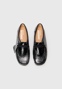 Black leather shoes with a rounded toe, textured surface, and stitched detailing. Features a lace fastening and a branded insole.