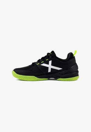 Czarne buty sportowe z textured górą, zielonymi akcentami i białym logo w kształcie X. Posiadają zieloną gumową podeszwę z zygzakowym wzorem.