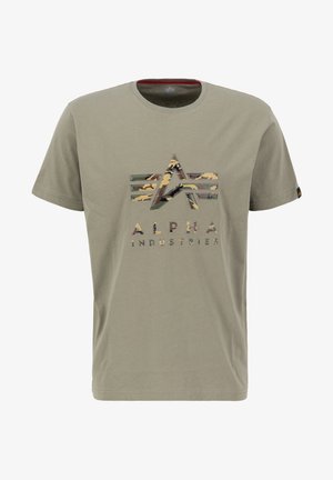 Oliva zeleni pamučni majica s kratkim rukavima koja sadrži logotip u kamuflažnom uzorku s geometrijskim dizajnom i natpisom "ALPHA INDUSTRIES" ispod.