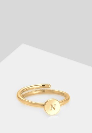 Bague plaquée or au design ouvert, comportant un disque circulaire gravé de la lettre "N". Fini lisse et brillant, style minimaliste.