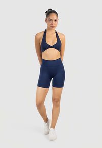 Mörkblå sportset med en halterneck-croptop och höga shorts, tillverkade av slät, stretchig tyg med en slimmad passform.