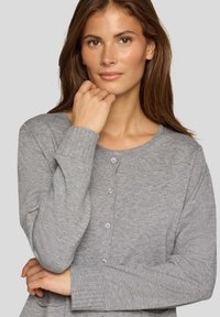 Grauer Cardigan mit rundem Ausschnitt, gerippten Bündchen und einer vorderen Knopfleiste mit fünf Knöpfen. Weiche Textur, schlichtes Design und mittlere Länge.