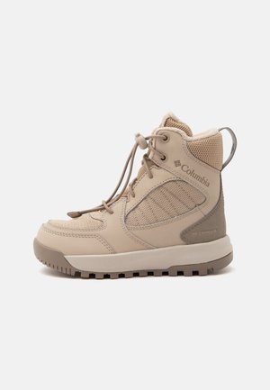Botte de randonnée Columbia beige imperméable, panneaux en mesh et cuir, coupe montante, semelle épaisse crantée et languette de tirage au talon.