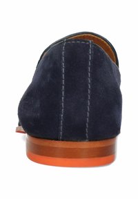 Marinblå mockaskor med slät läderfoder, sydda detaljer och en träsoffa med orange accent.