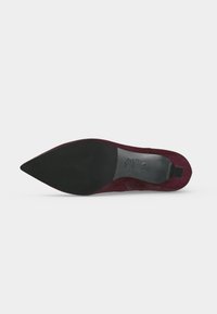 Chaussure à talon haut en daim bordeaux à bout pointu, vue de la semelle avec grip en caoutchouc noir et marquages de taille à l'arrière.