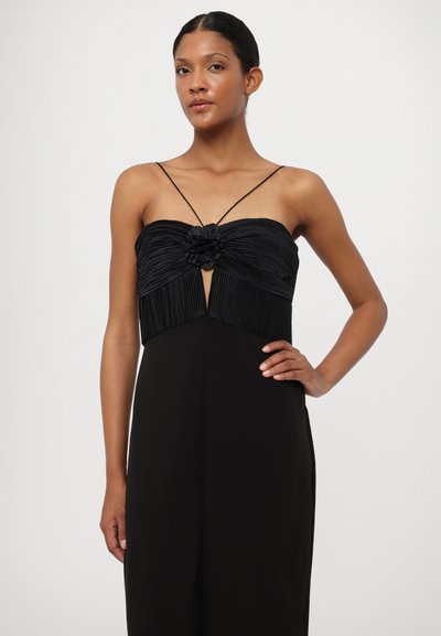 Zwarte jumpsuit met een strapless geplooide buste, bloemaccent in het midden en slanke bandjes. Glad materiaal met een aansluitende snit.