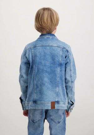 Lichtblauwe denimjack met een klassiek ontwerp, knoopsluiting en leren logo-embleem op de rug, gecombineerd met bijpassende denim jeans.