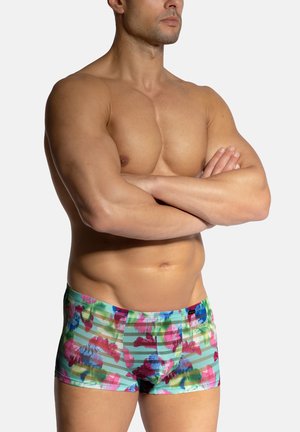 Bunte, floral gemusterte Badehosen aus leichtem Stoff, mit Farbtönen von Grün, Pink und Blau sowie subtilen horizontalen Streifen.