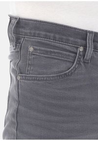 Vaqueros de mezclilla gris con un diseño ajustado, que cuentan con un bolsillo frontal con remaches de metal, costuras en contraste y una textura suave.
