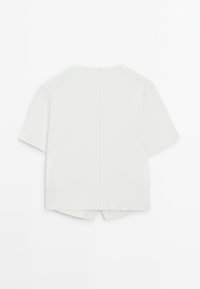 Valkoinen lyhythihainen toppi pyöreällä pääntiellä, jossa on takasauma ja halkiot helman kohdalla. Valmistettu sileästä, kevyestä kankaasta.