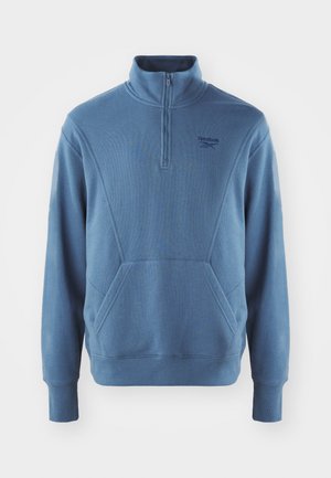 Blue Reebok pullover sweatshirt with a quarter-zip, ribbed cuffs, and a kangaroo pocket. Made from soft, textured fabric with subtle branding.