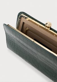 Πράσινο πορτοφόλι από ψεύτικο κροκοδείλινο δέρμα με χρυσή κλίση και λεπτομέρειες φερμουάρ, διαθέτει λείο εσωτερικό και πολλές θήκες.