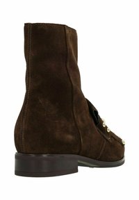 Bruine suède enkellaars met een ronde neus, platte hak, decoratieve metalen studs en stiksels aan de zijkant.