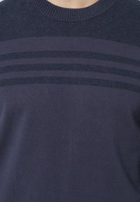 Navy blue knitted sweater featuring a ribbed crew neckline and horizontal stripe pattern across the chest in a slightly darker shade.