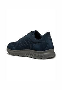 Sneaker in suede blu navy con finitura testurizzata, suola in gomma e design curvo. Presenta dettagli cuciti e un linguetta sul tallone.