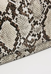 Borsa in pelle di serpente con una palette di colori nero, bianco e beige, caratterizzata da un motivo a diamante testurizzato e rifiniture lisce lungo i bordi.