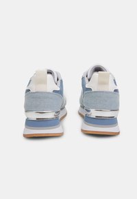Sinine teksakangast sneakers valgete aktsentidega, hõbedane vahekiht, pehmendatud kaelus ja lame pruuni kummist välistald. Omab tõmbluku silti kannal.