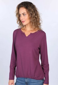 Langärmliges, pflaumenfarbiges Oberteil mit rundem Ausschnitt und elastischem Bund. Verfügt über eine subtile Vordernahtdetail und eine weiche Stoffoberfläche.