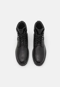 Bottes cheville en cuir noir à finition lisse, bout rond, design à lacets, col rembourré et semelle en caoutchouc texturée.